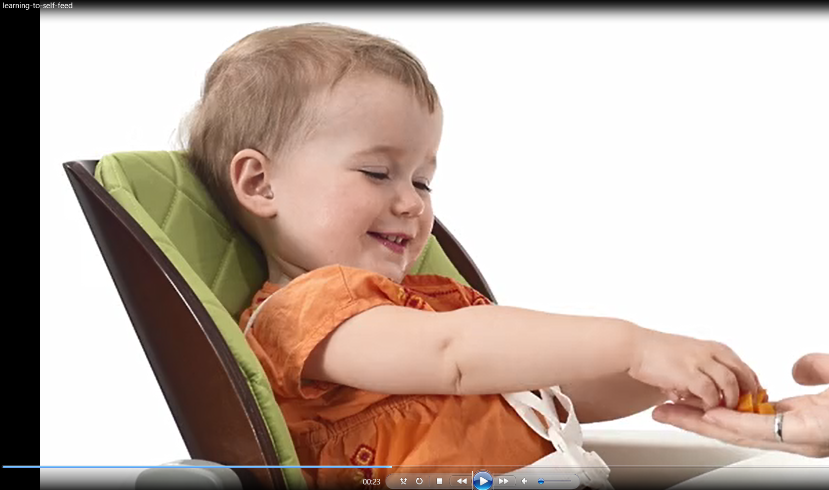 Baby in high chair learning to self-feed