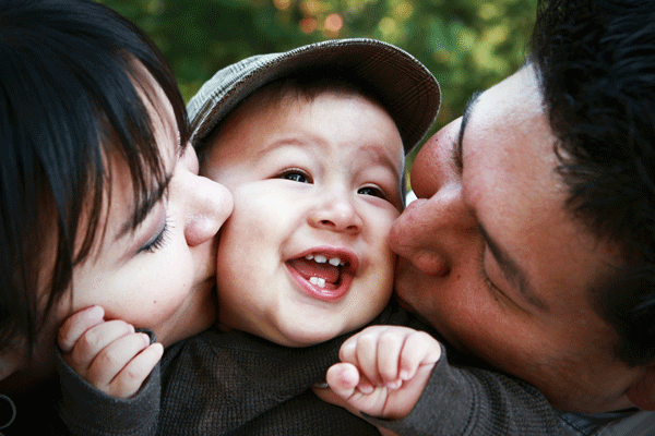 Parents kissing baby