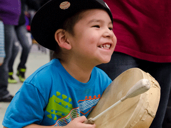 Indigenous child playing drum