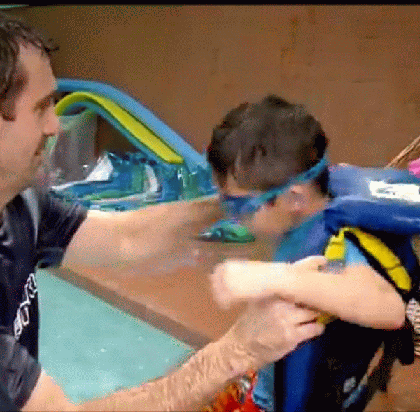 image of father helping child with life jacket into a pool