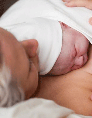 Woman after birth with baby on her chest