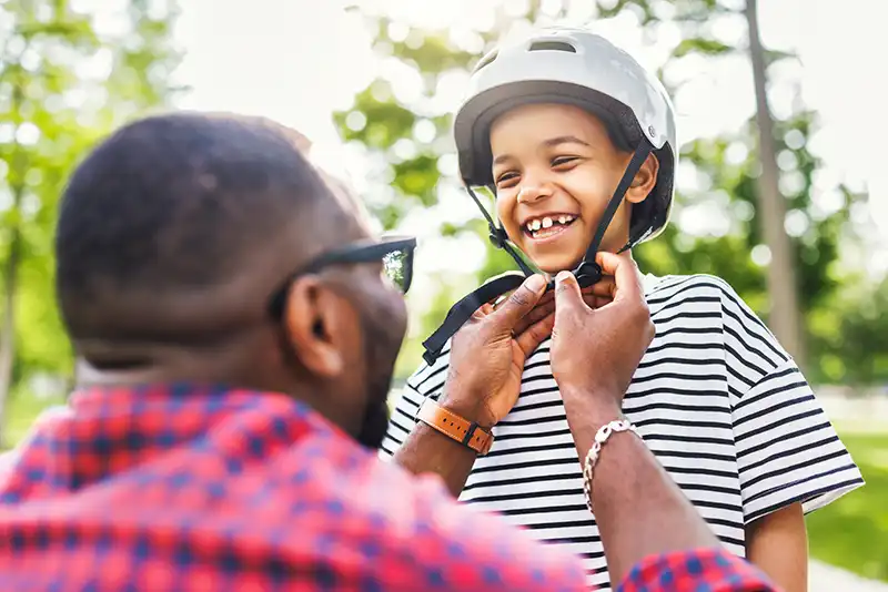 adult helping child to wear and adjust helmet