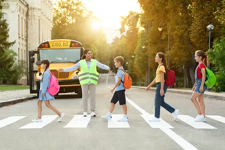 children going through zebra crossing and being helped by adult