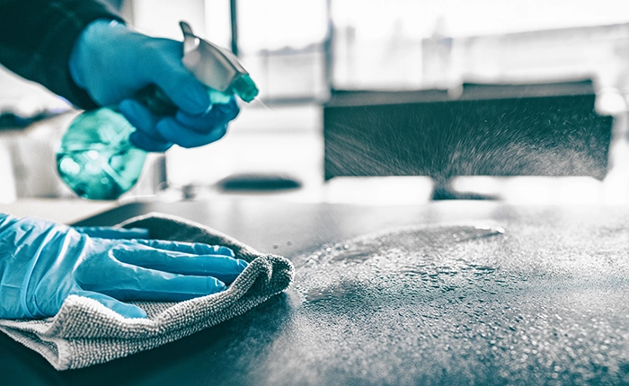 Person cleaning and disinfecting surface
